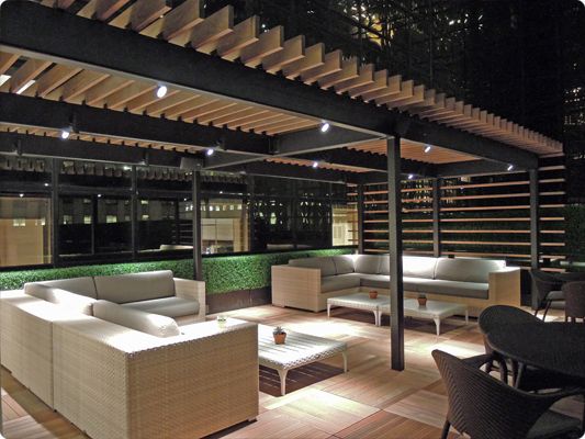 an outdoor living area with couches, tables and chairs at night in the evening