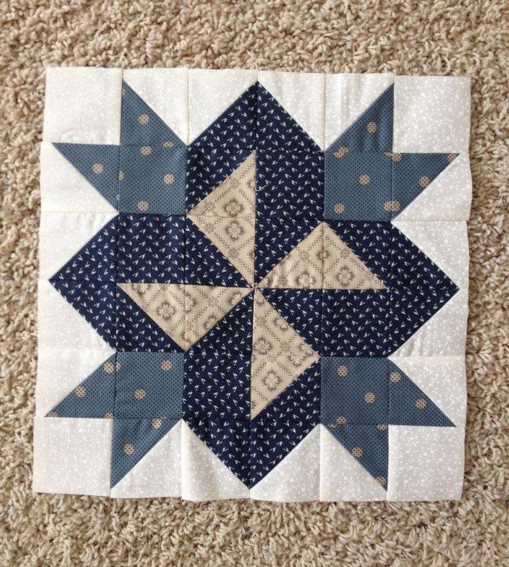 a blue and white patchwork quilt on the floor with a star in the middle