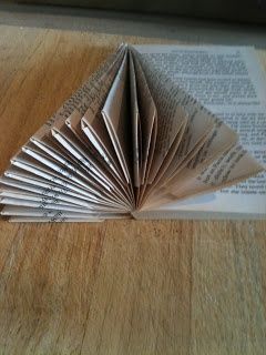 an open book sitting on top of a wooden table with pages folded in the shape of a triangle