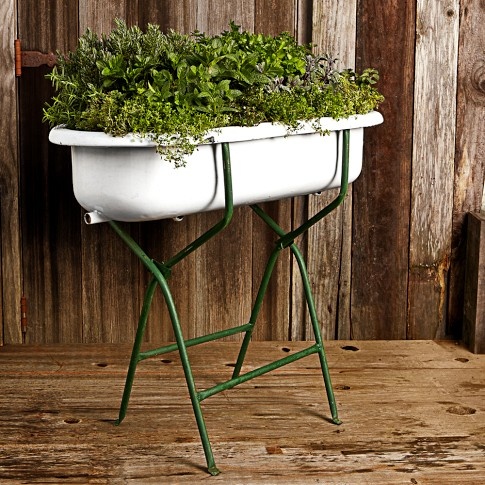 a white planter sitting on top of a green metal stand next to a wooden wall