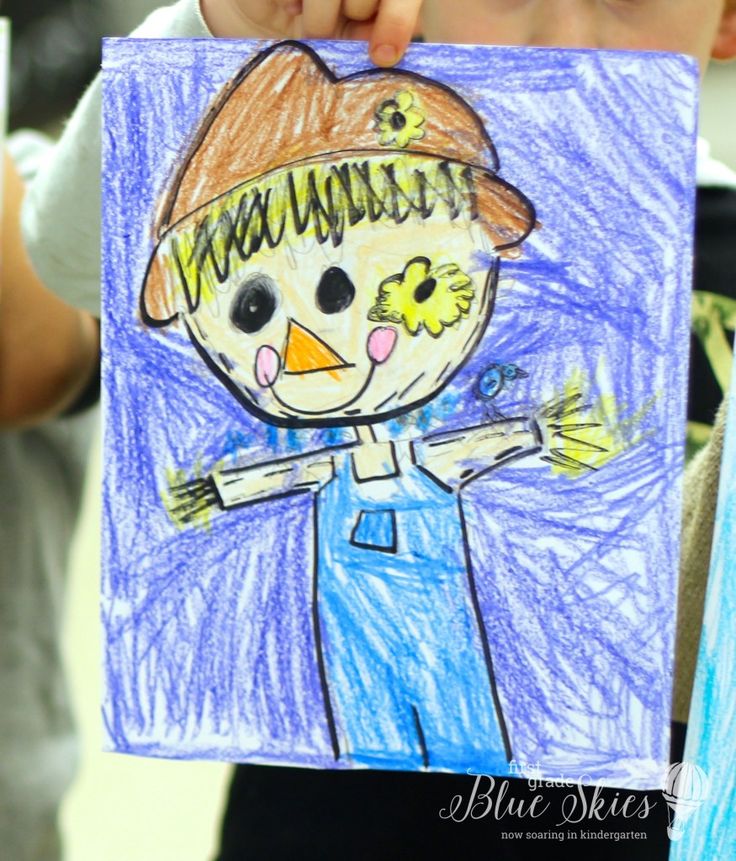 a child holding up a drawing of a scarecrow