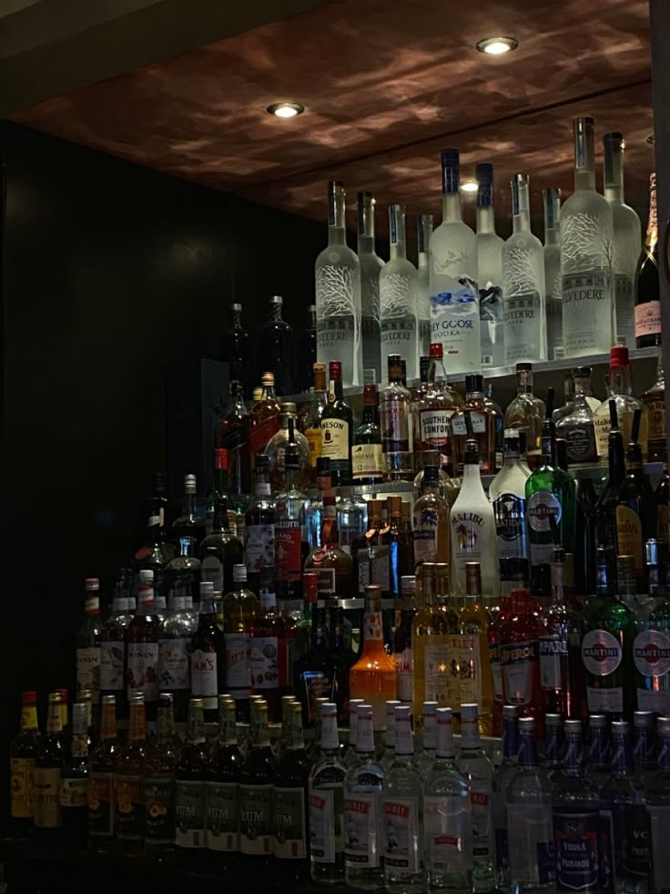 many bottles and glasses are lined up on the bar