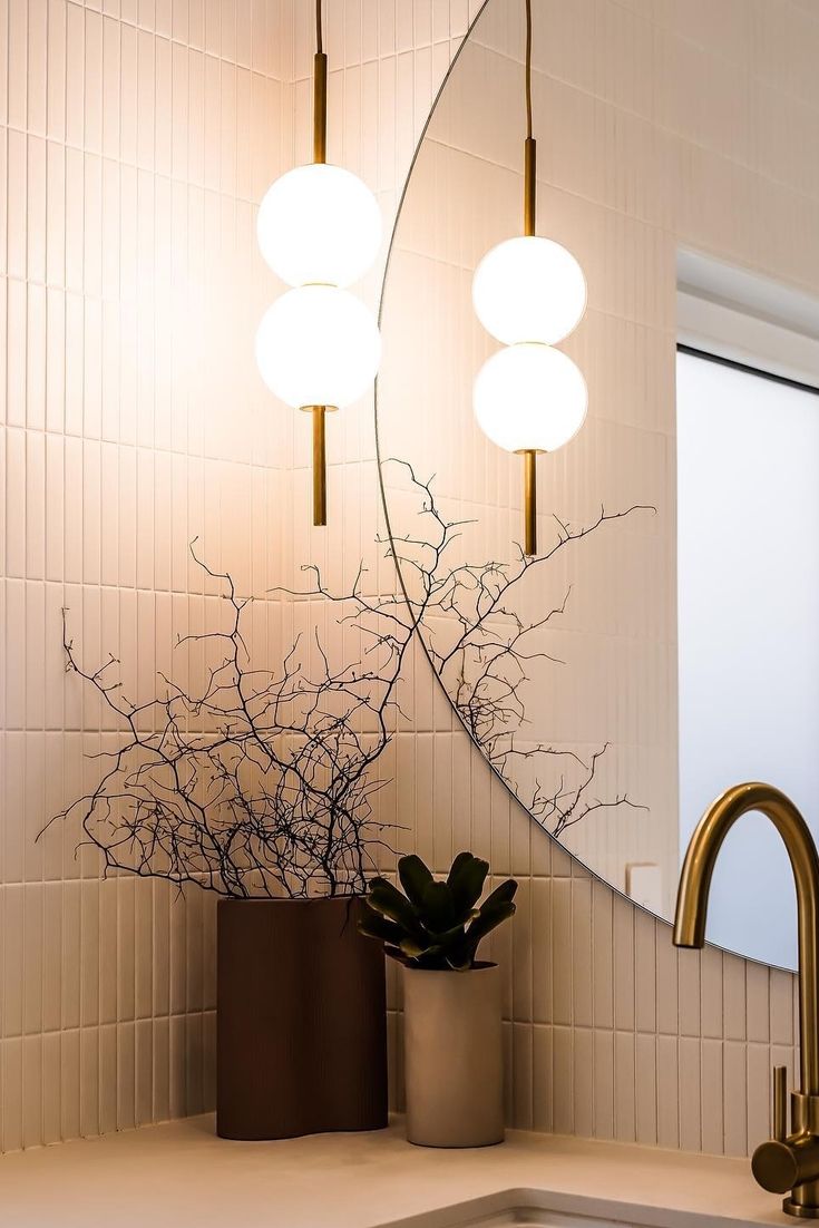 a bathroom sink with a mirror and two lights on the wall above it next to a potted plant