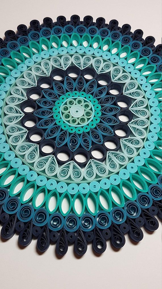 a circular doily made out of blue, green and black paper with circles on it