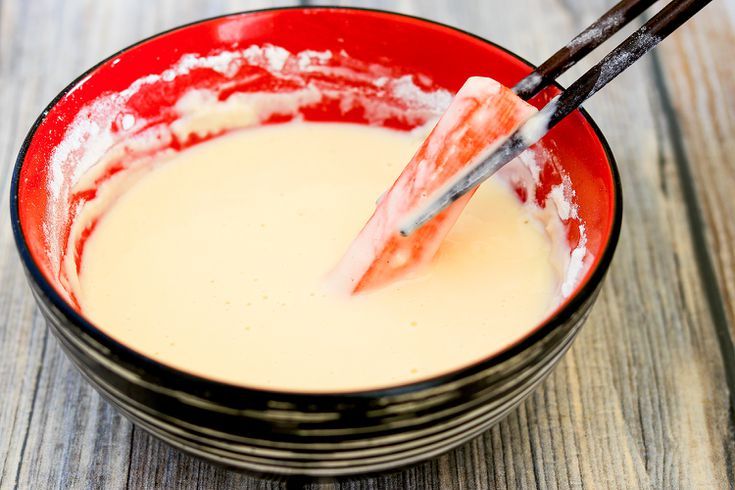 a red bowl filled with cream and two black chopsticks sticking out of it