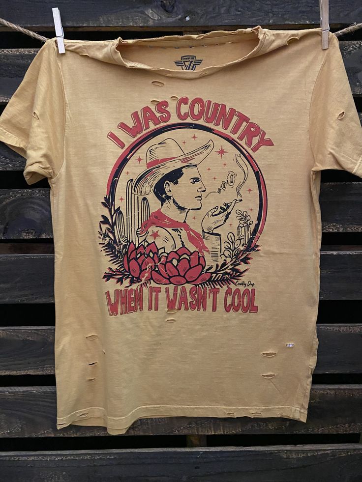 I Was Country When it wasn't Cool unisex distressed T shirt in vintage wash white and Mustard Vintage country western cowboy T shirt 40 Singles Jersey 100% Cotton Premium quality ringspun and compacted cotton Fine Cotton Jersey that is pigment dyed for a more vintage look Features tears and destroyed features at neck and on body Each piece is unique as this process is done by hand! 3.8 oz Made In USA Every garment dye item can be a slightly different shade in color since this is a laundry dye pr Vintage Summer T-shirt For Rodeo, Vintage Washed T-shirt For Spring, Retro T-shirt For Summer Country Concerts, Vintage Faded T-shirt Pre-washed, Western Style T-shirt For Ranch In Summer, Casual Distressed Tops For Rodeo, Western Style Summer T-shirt, Vintage Acid Wash Pre-washed T-shirt, Western Style Cotton T-shirt For Rodeo