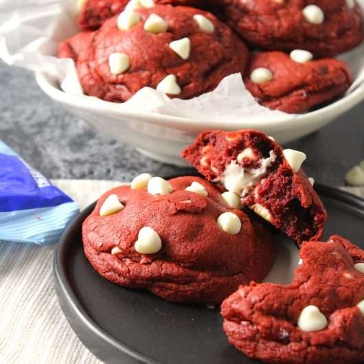 red velvet cookies with white sprinkles are on a black plate next to a blue napkin