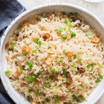 a white bowl filled with rice and peas on top of a table next to a black napkin