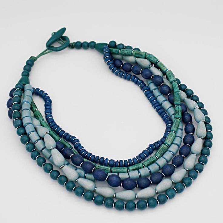 Multiple strands of blue wooden beads are layered together to make up this beautiful statement necklace. Each strand features a different shape and size bead. Hung on a toggle closure, the length of the necklace is made to be shorter to accentuate your neckline. Necklace hangs 18"in length  Made to match UN23E01 BLUE Care Instructions: Remove jewelry when applying perfumes, creams, washing hands, etc. Do not store in direct sunlight. To restore color and shine, apply a drop of oil with a soft cloth Washing Hands, Fashion Capsule Wardrobe, Jewerly Beads, Colorful Necklace, Necklace Colorful, Bold Necklace, Wooden Accessories, Necklace Blue, Lovely Necklace