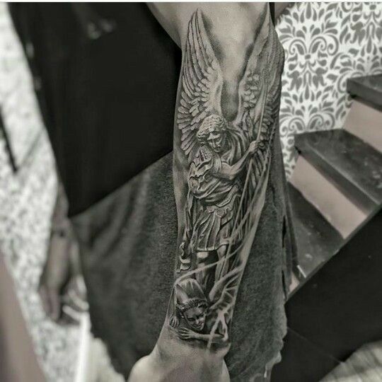 a man's arm with an angel and demon tattoo on the left side of his arm