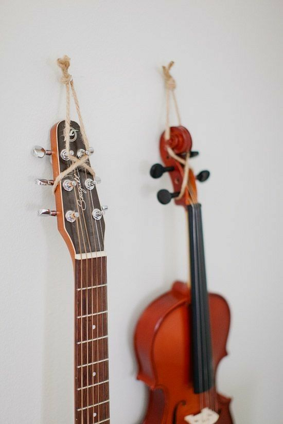 two guitars are hanging on the wall next to each other, with strings attached to them