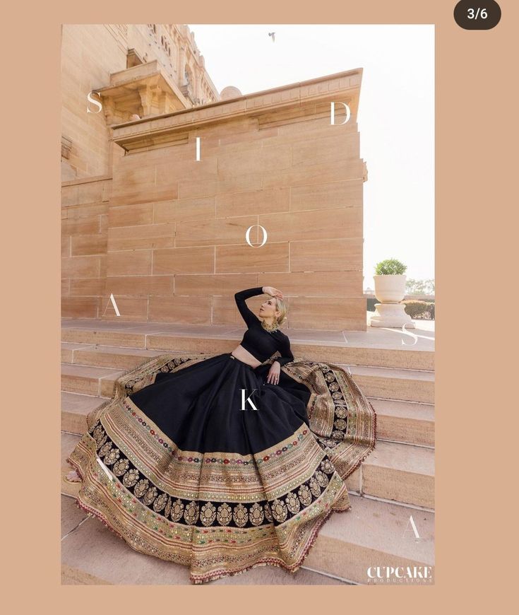 a woman in a black and gold dress sitting on some steps