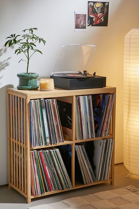 a record player sitting on top of a wooden shelf next to a plant in a vase