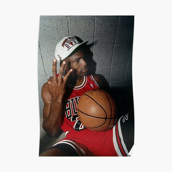 a man sitting on the floor with a basketball in his hand while talking on a cell phone