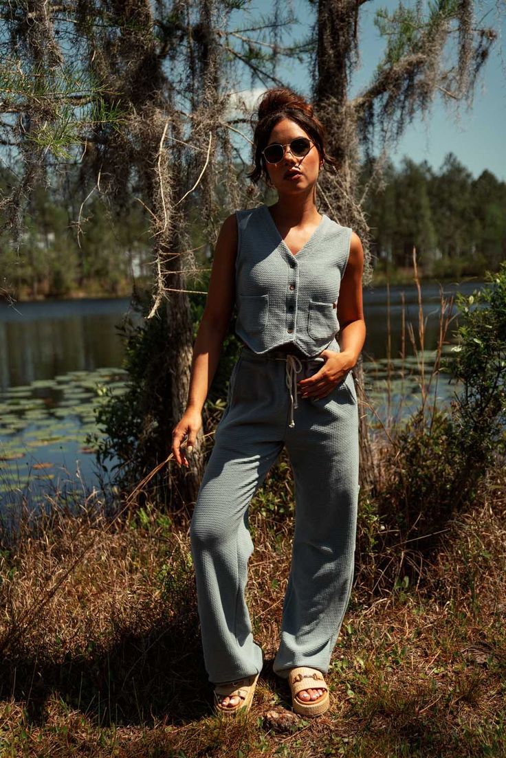 This perfect Summer top can be worn buttoned up on its own or open as a true vest! Our super soft waffle fabric is lightweight and breathable and the perfect Summer companion! Our vest includes 2 small pockets and buttons down center front. 50% Polyester | 50% Cotton Made in Los Angeles, CA SIZE GUIDE Sarah is 5'10 and wearing a size S vest. (Shown in Oak and Slate Blue) Natalie is 5'5 and wearing a size S vest. (Shown in Slate Blue) Brittney is 5'7 and wearing a size M vest. (Shown in Oak and S Casual Denim Vest With Button Closure, Casual Sleeveless Sweater Vest For Loungewear, Casual Cotton Sweater Vest For Day Out, Casual Spring Tank Top With Pockets, Casual Tank Top With Pockets For Spring, Casual Sweater Vest With Buttons, Casual Everyday Vest For Spring, Spring Casual Loungewear Vest, Casual Workwear Vest With Pockets