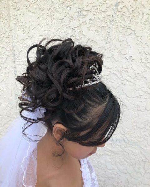 a woman wearing a tiara and veil with her hair in a bunt style