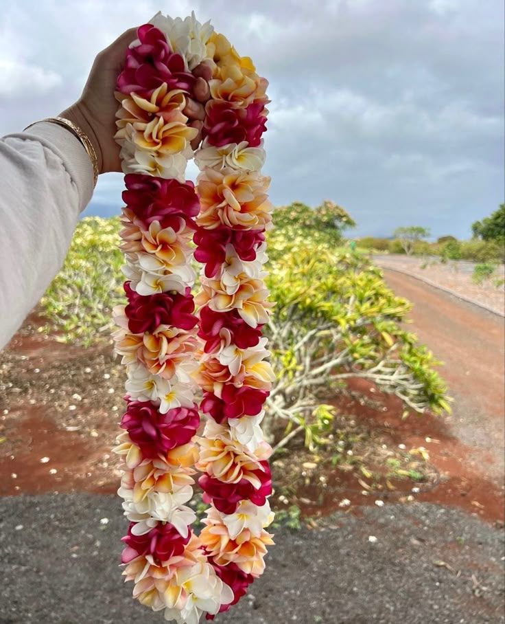 a person holding up a lei with flowers on it