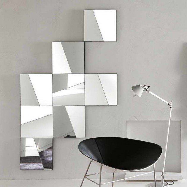 a black chair sitting in front of a white wall with mirrors on the wall behind it