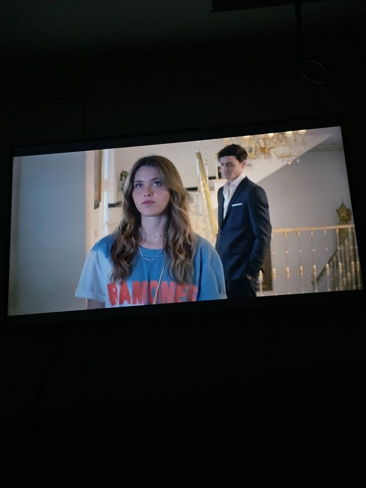 a man and woman standing in front of a tv screen with the same image on it