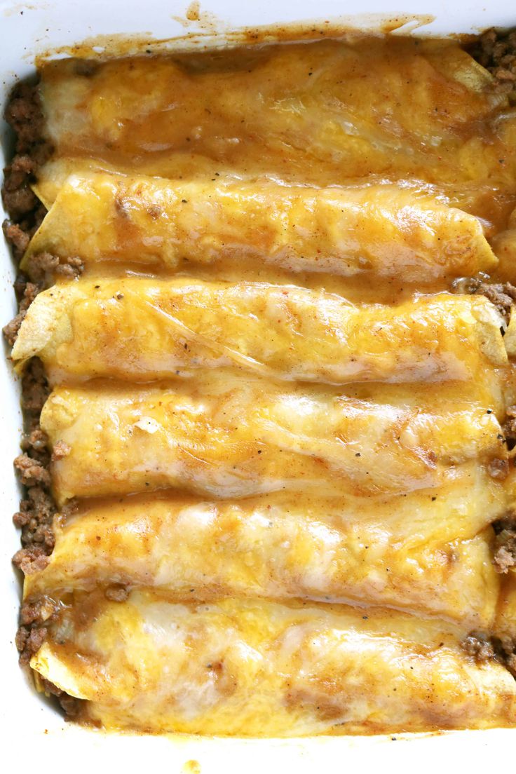 an enchilada casserole in a white dish with meat and cheese