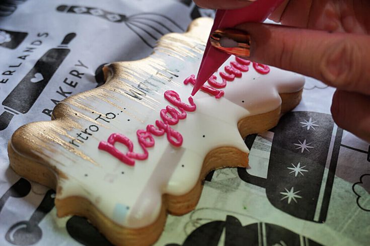 a person cutting into a decorated cookie with the word happy birthday written in pink icing