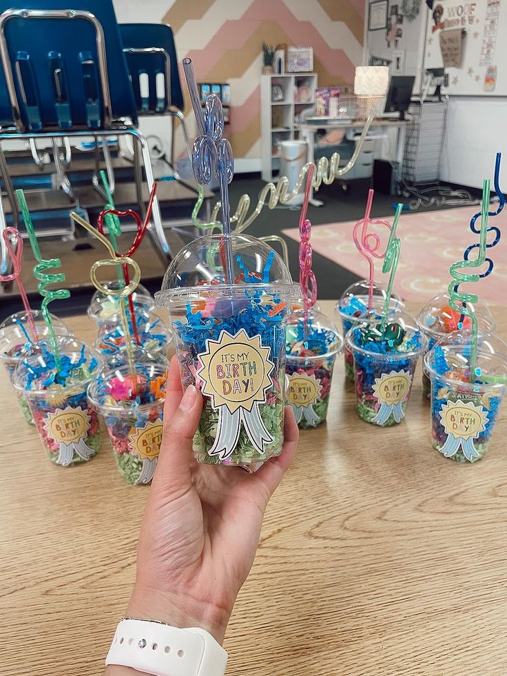 someone is holding up their birthday cupcakes in front of the party cups on the table