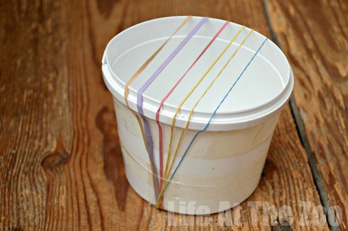 a white plastic container with multicolored stripes on the lid sitting on a wooden table