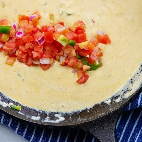 a skillet filled with cheese and toppings on top of a blue striped towel