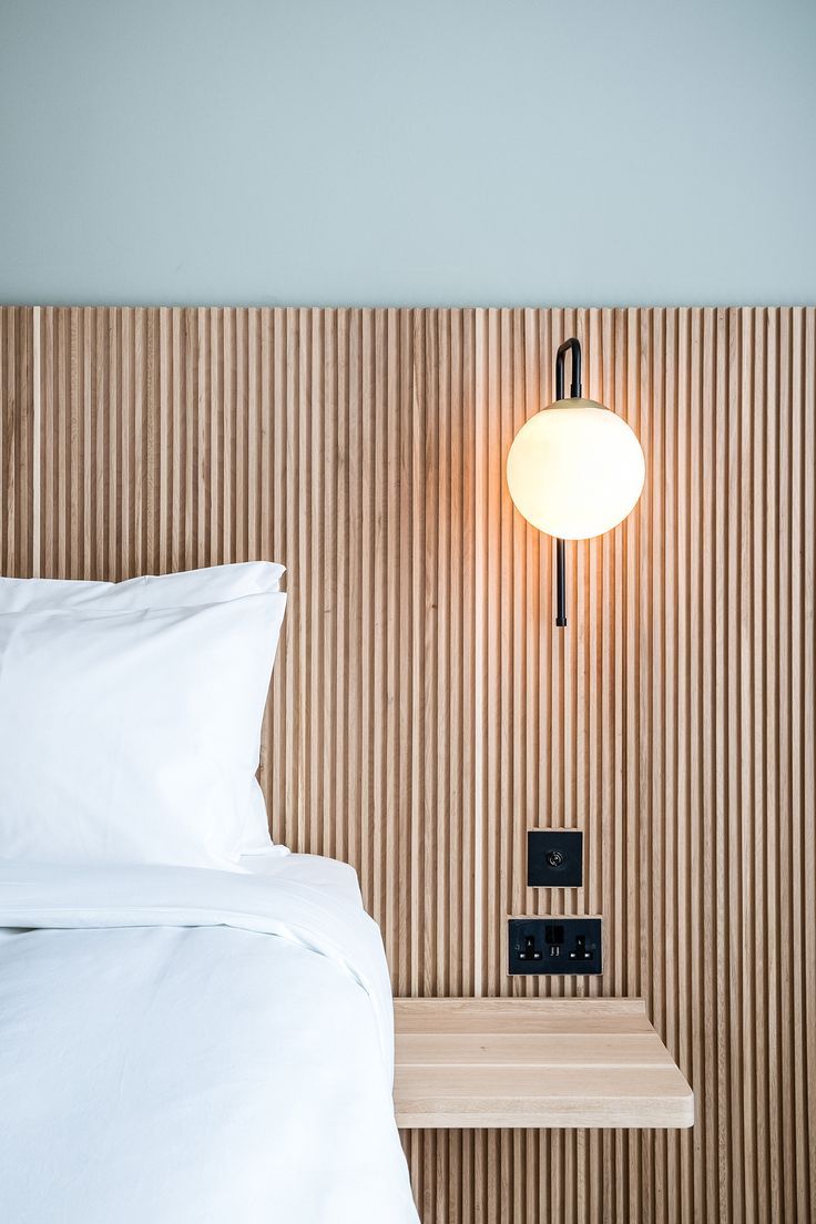 a white bed sitting next to a night stand with a lamp on top of it