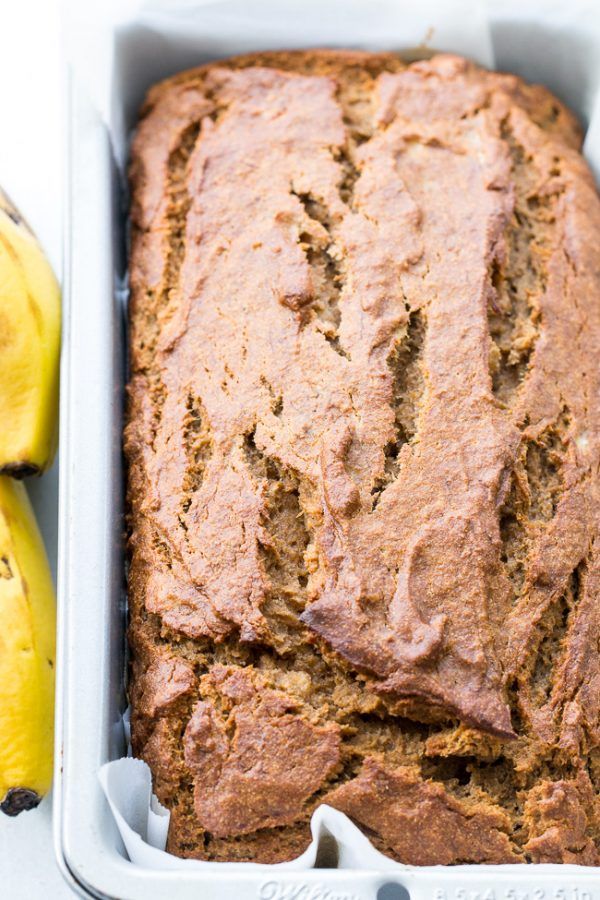 a loaf of banana bread in a pan next to two bananas