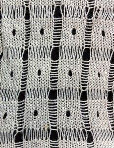 a white crocheted tablecloth with black dots on the edges and lines drawn across it