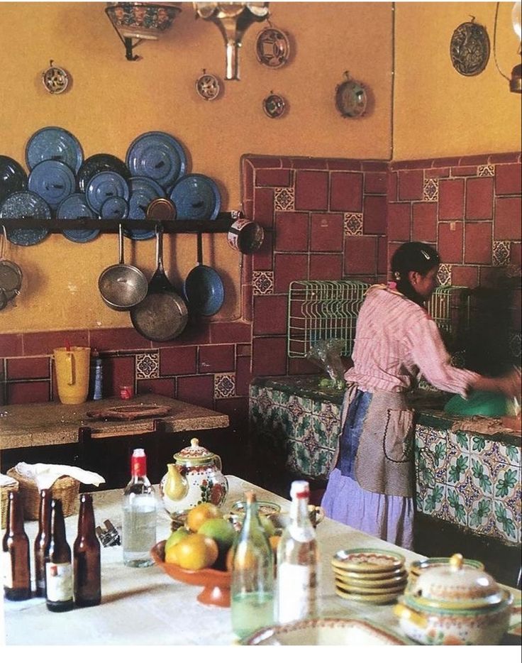 a woman in a kitchen preparing food on top of a counter next to plates and bowls