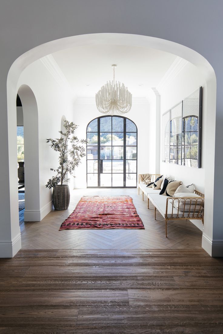 a living room with wood flooring and arched doorway leading into the dining area that has a chandelier hanging from the ceiling