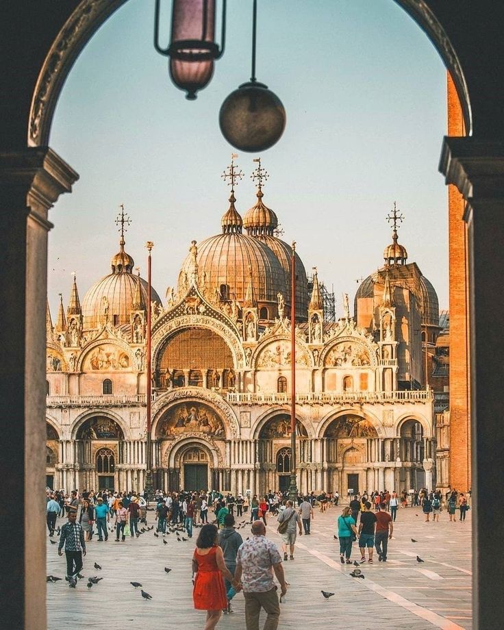 people are walking around in front of an ornate building with many spires and domes