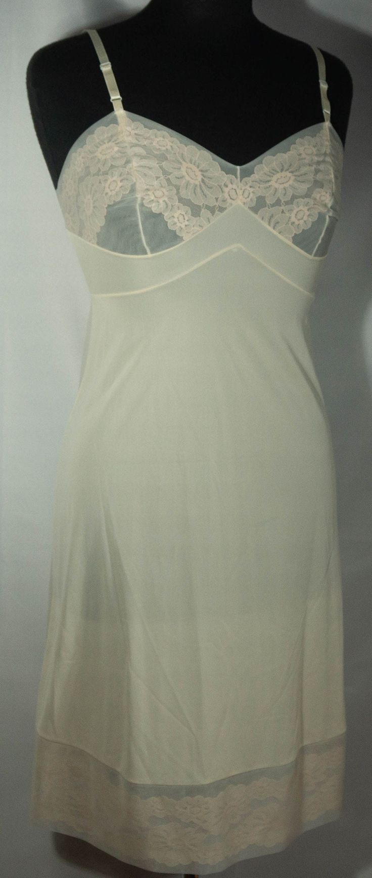 "Here's a late 60s/early 70s made in U.S.A. off white cream color slip dress that is in great condition with the iconic Vanity Fair label. This slip has adjustable shoulder straps, fitted bodice top and skirt slip to the knee lower half that's trimmed in lace. Perfect! The original Vanity Fair label says it's a size 32 and laid-flat measurements are included here for you to check the fit - it seems tiny! This is a lovely slip is a basic that's so versatile and makes a great vintage wardrobe stap Slip Dress Undergarment, 70s Slip Dress, Vintage Slip Skirt, Fitted Cream Camisole With Built-in Bra, Beige Fitted Camisole, White Sheer Camisole Slip Dress, White Fitted Sheer Camisole, White Sheer Fitted Camisole, White Sheer V-neck Slip Dress