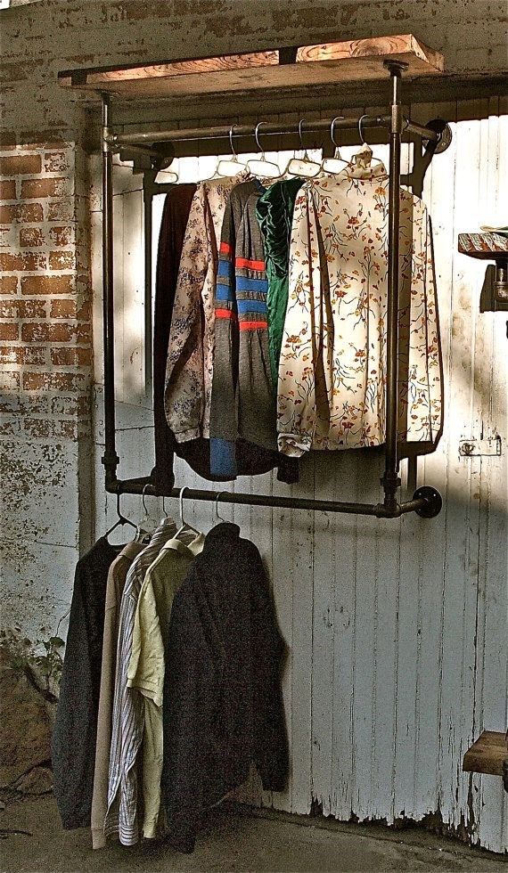 clothes are hanging on an iron rack in front of a brick wall and wooden door