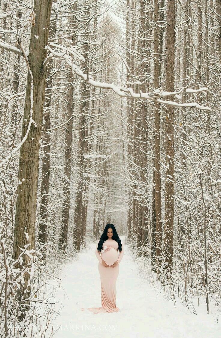 a woman standing in the middle of a snow covered forest