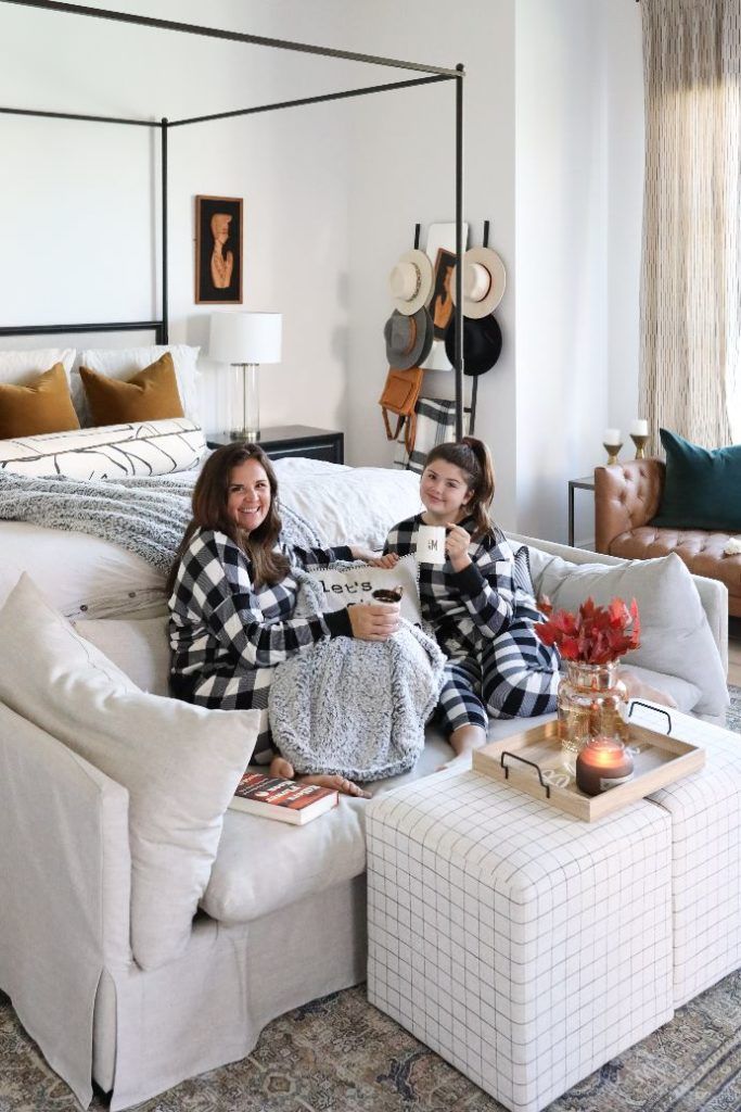 two women sitting on a white couch in a living room next to a coffee table