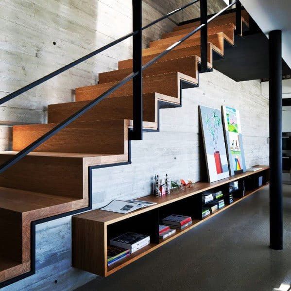 the stairs are made of wood and metal, with bookshelves below them on either side