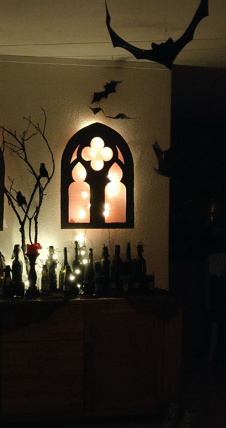 a table with bottles and candles on it in front of a wall decorated with bats