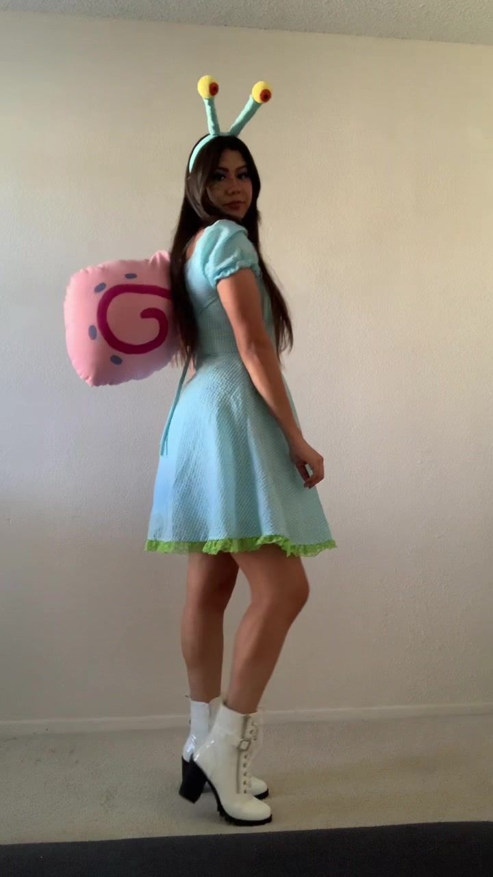 a woman in a blue dress holding a pink ballon and wearing a bug costume