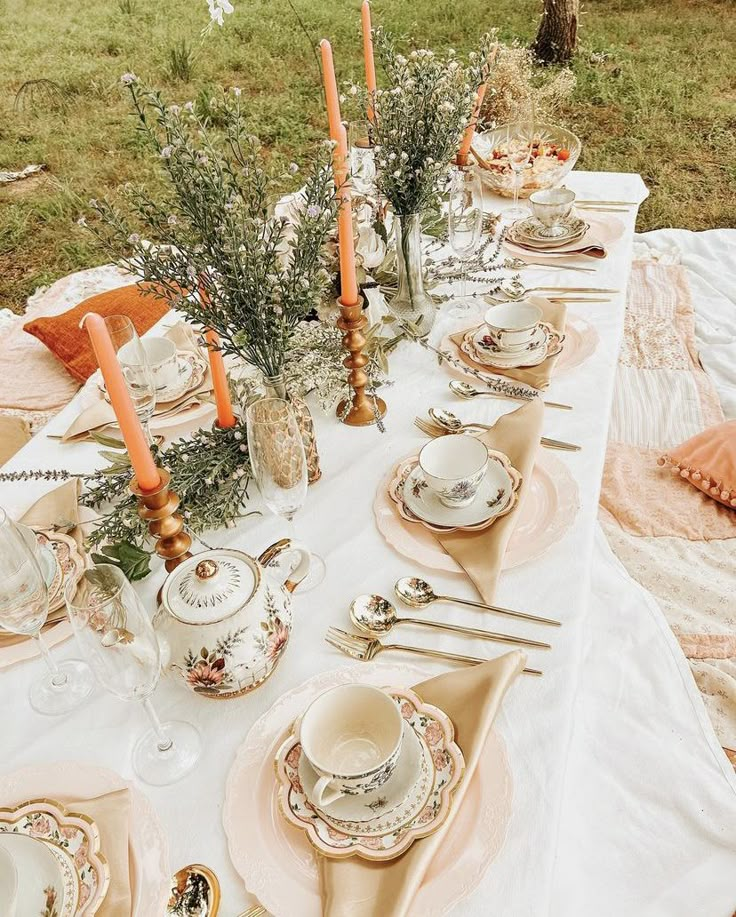 an outdoor table set with plates, silverware and candles