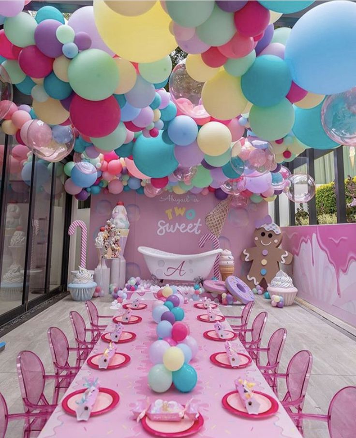 a table set up for a baby shower party with lots of balloons and pastel colors