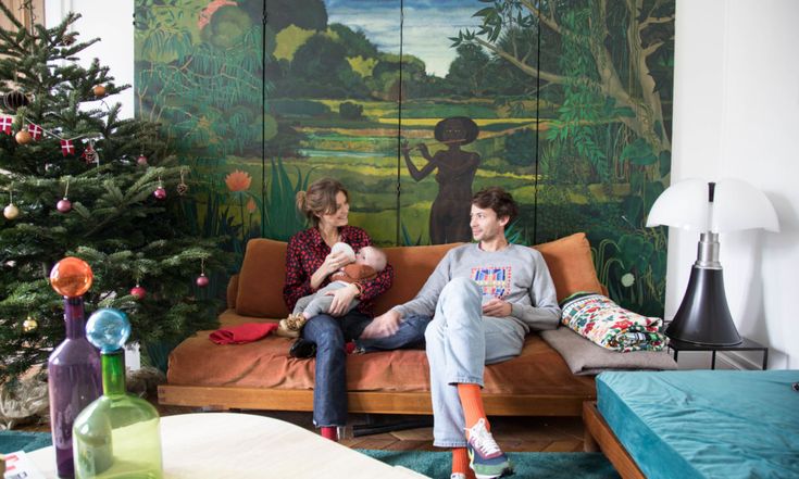 two people sitting on a couch in front of a painting