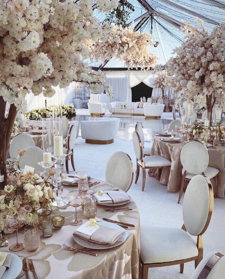 tables set up for an event with white flowers and greenery on the tablecloths