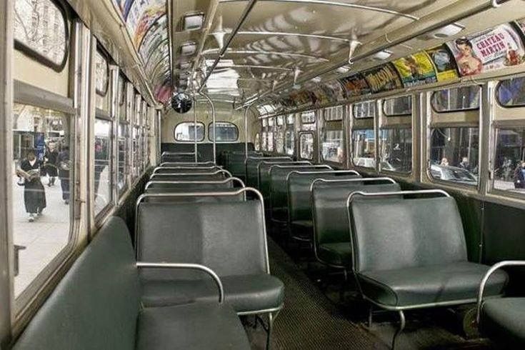 the inside of a subway car with green seats and advertisements on the wall behind it