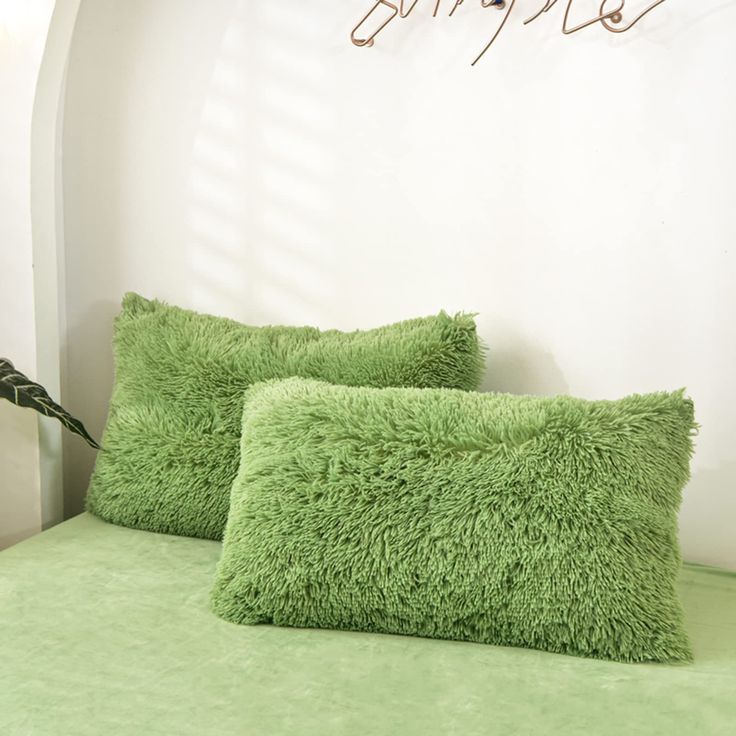 two green pillows sitting on top of a bed