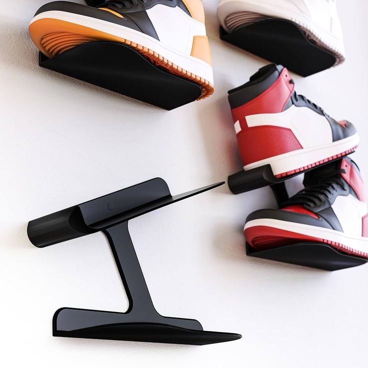 four pairs of shoes hang on the wall next to a pair of shoe hooks