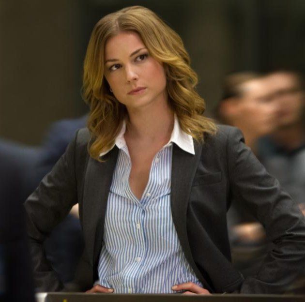 a woman standing in front of a group of people wearing suits and ties, looking off to the side