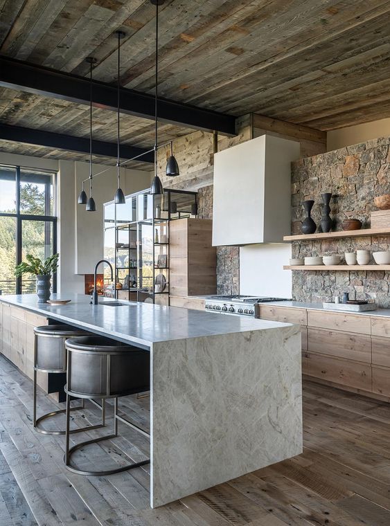 a kitchen with wooden floors and stone walls, along with an island in the middle